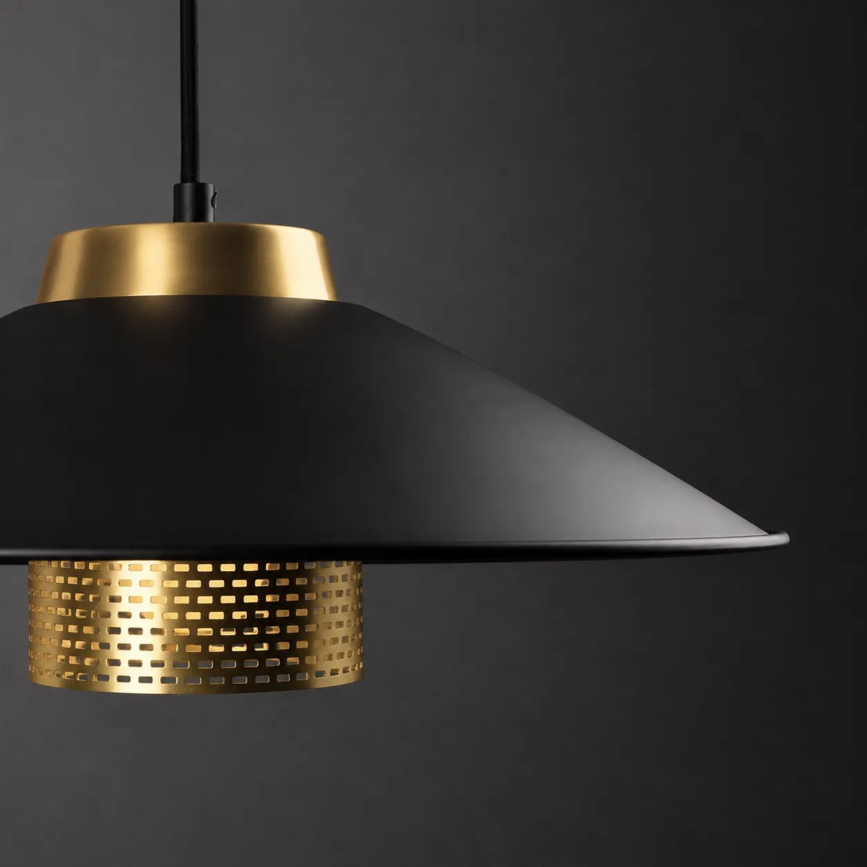 Close angled view of the matte black conical shade and brass center structure